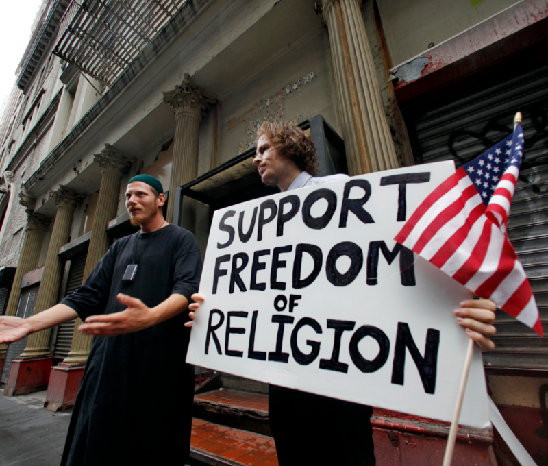 men protestors holding a sign stating"support freedom of religion"